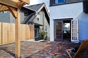 Tearing down an old garage, allowed the client to build a patio, raising the grade to meet the new French doors from the dining room. The new arbor provides a sheltered seating area. Planting pockets were built into the patio on all sides.